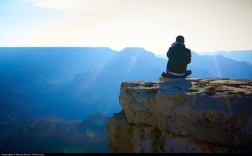 Une personne méditant face à un paysage au lever du soleil